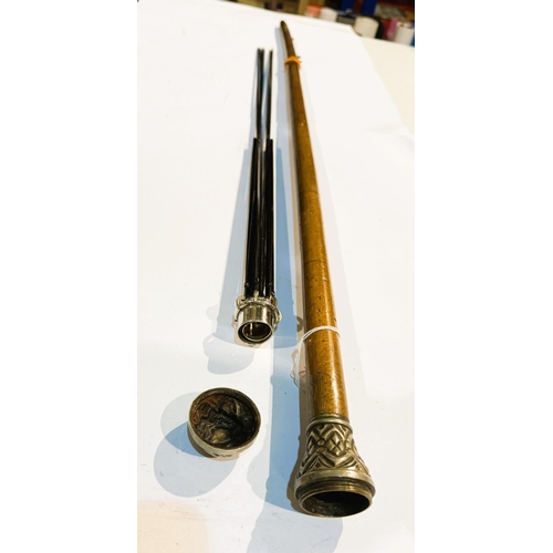 194 - An early 20th Century walking cane with embossed metal finial with screw top concealing an umbrella ... 