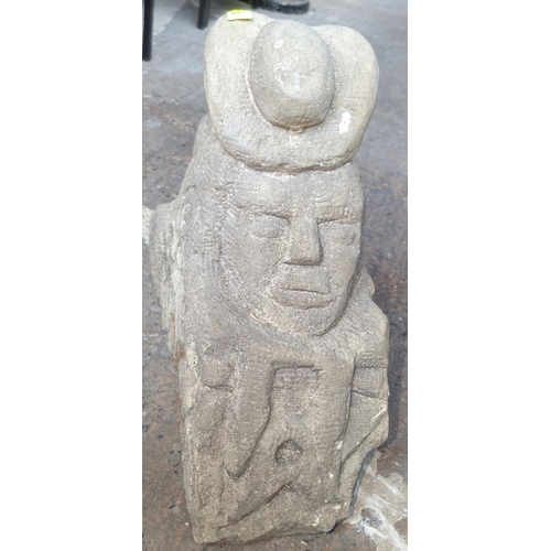 1052 - A medieval type stone carving of a figure head down over carved face with other patination, ht 43cm.