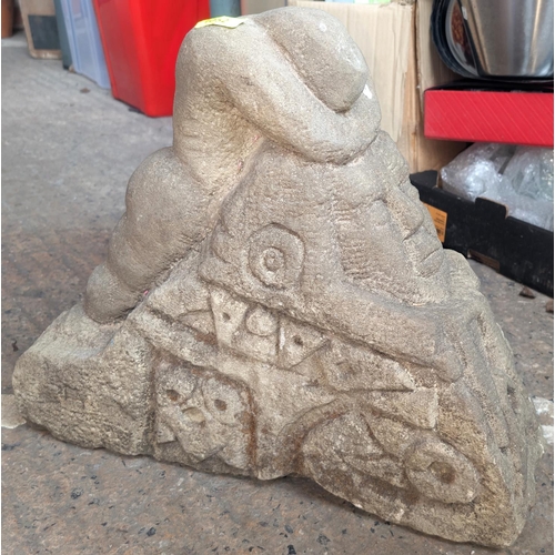 1052 - A medieval type stone carving of a figure head down over carved face with other patination, ht 43cm.