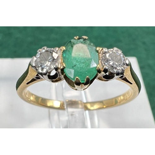 727 - A yellow metal ring stamped 18ct. set with a central emerald flanked by 2 diamonds, 2.5gms, size M