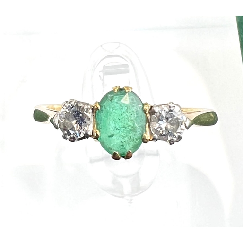 727 - A yellow metal ring stamped 18ct. set with a central emerald flanked by 2 diamonds, 2.5gms, size M