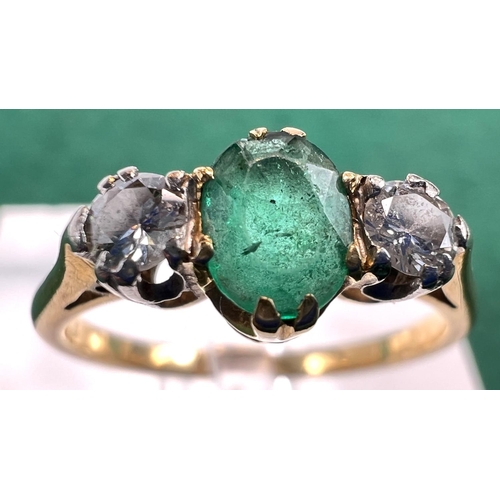 727 - A yellow metal ring stamped 18ct. set with a central emerald flanked by 2 diamonds, 2.5gms, size M