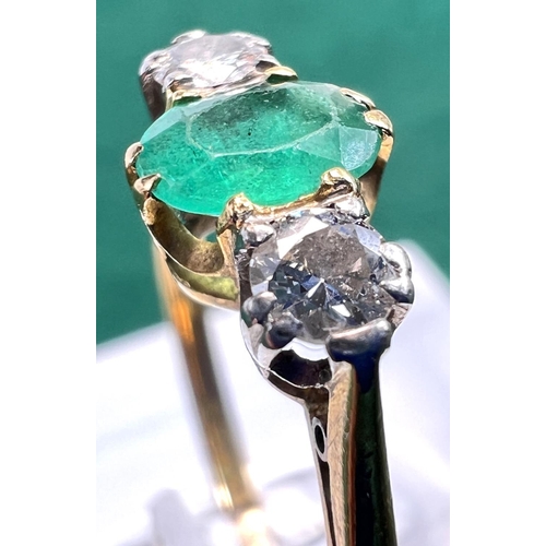 727 - A yellow metal ring stamped 18ct. set with a central emerald flanked by 2 diamonds, 2.5gms, size M