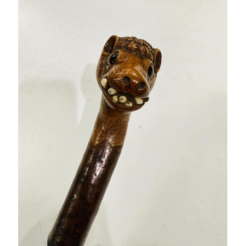 177 - A vintage rustic walking stick with carved head finial of a snaggle-toothed monster, 90cm.