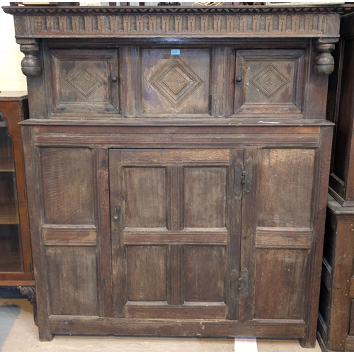 1010 - An 18th century oak court cupboard with twin diamond carved upper doors and framed and panelled sing... 