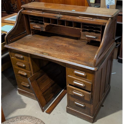 989 - An Art Deco oak roll top desk with four drawers to each pedestal, length 121cm, depth 67cm.