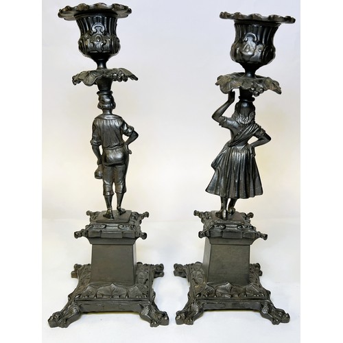 14 - A pair of cast metal candle sticks with male and female column with squared base and a small spelter... 