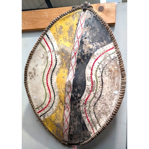 57 - A late 19th/early 20th century African (possibly Masai) hide shield with painted decoration to the f... 