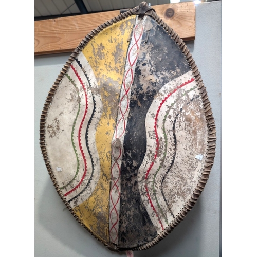 57 - A late 19th/early 20th century African (possibly Masai) hide shield with painted decoration to the f... 