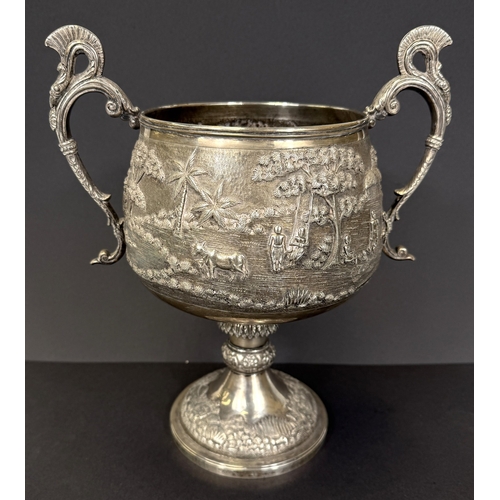 601 - A large late 19th century Indian white metal two-handled pedestal trophy cup with extensive relief d... 