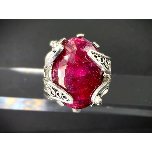 641 - A white metal dress ring set with large natural cut ruby stone in elaborate setting stamped 925