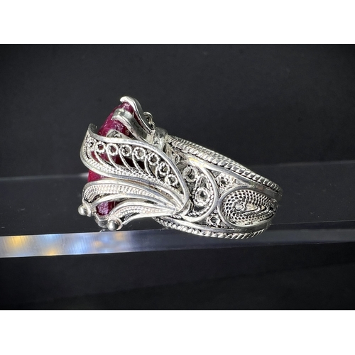 641 - A white metal dress ring set with large natural cut ruby stone in elaborate setting stamped 925