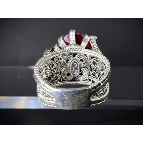 641 - A white metal dress ring set with large natural cut ruby stone in elaborate setting stamped 925