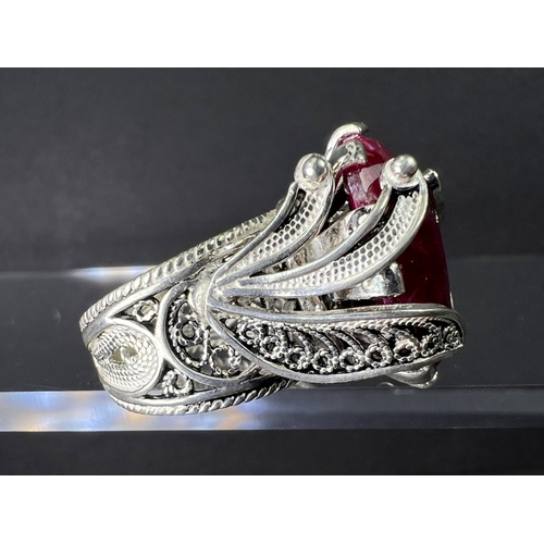 641 - A white metal dress ring set with large natural cut ruby stone in elaborate setting stamped 925