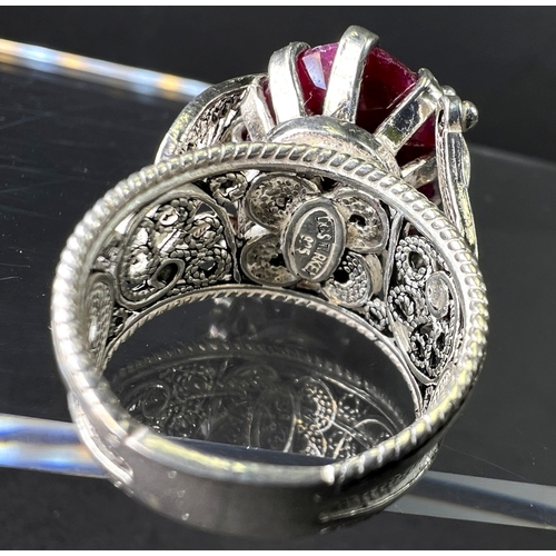 641 - A white metal dress ring set with large natural cut ruby stone in elaborate setting stamped 925