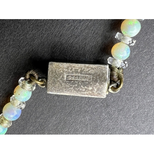 694 - An opal and crystal necklace formed fom a row of round opal beads spaced by faceted crystal rondelle... 