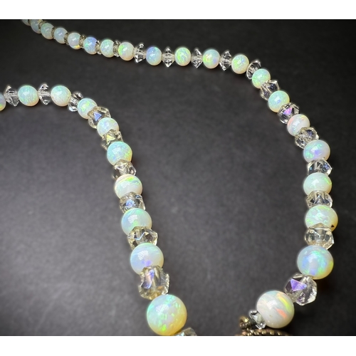 694 - An opal and crystal necklace formed fom a row of round opal beads spaced by faceted crystal rondelle... 