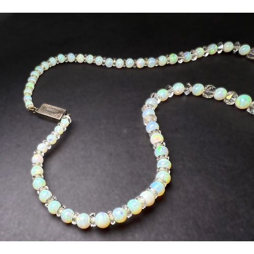 694 - An opal and crystal necklace formed fom a row of round opal beads spaced by faceted crystal rondelle... 