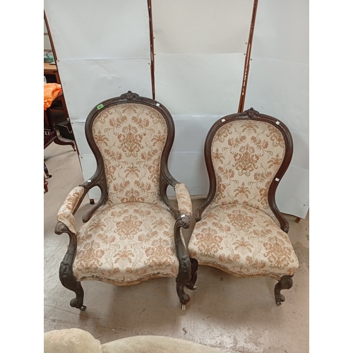 768 - A Victorian carved mahogany framed pair of Ladies and Gents armchairs upholstered in floral pattern.