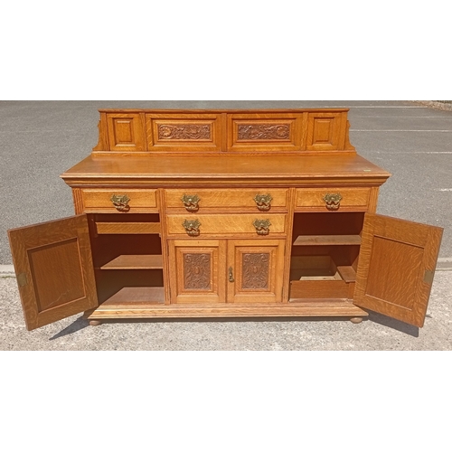 817 - A large golden oak Scottish sideboard with carved panel doors, four drawers and 3 cupboards.