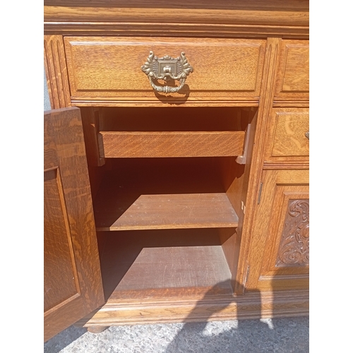 817 - A large golden oak Scottish sideboard with carved panel doors, four drawers and 3 cupboards.