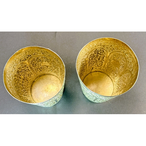 763 - A matched pair of early 20th century Indian white metal beakers with scrolling decoration 12.7oz.