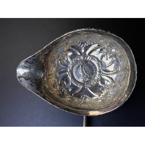 552 - An 18th century punch ladle with inset George II coin, with embossed decoration and twisted bone han... 