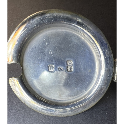 557 - A circular monogrammed mustard pot with blue glass liner, London 1898; a chased hallmarked silver ve... 
