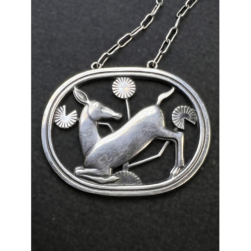 630B - GEORG JENSEN: an oval silver pendant of deer kneeling amongst stylised foliage, stamped to reverse G... 