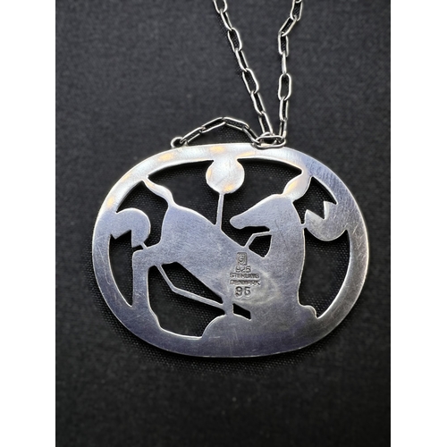 630B - GEORG JENSEN: an oval silver pendant of deer kneeling amongst stylised foliage, stamped to reverse G... 