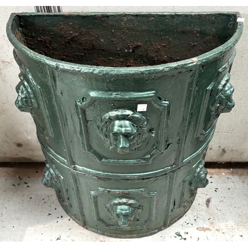 10A - A pair of green painted demi-lune cast iron troughs with lion mask decoration, diameter 55cm.