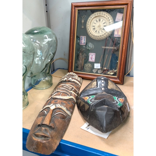 20B - A cased diorama on golf clock, Nelson framed poster, two African masks and a print.