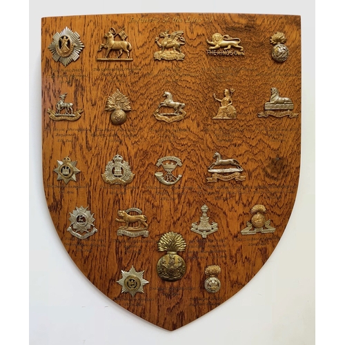 104 - 26 Infantry cap badges mounted on shield.   Good selection beautifully mounted on varnished wooden s... 