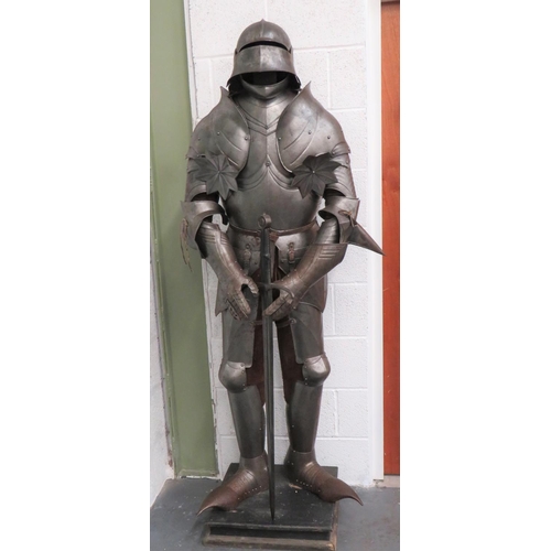Victorian Gothic Revival Full Hall Armour and Sword
15th century style, German full suit comprising Salades (Sallet) helmet with visor.  Gorget with chin protector, 2 section plate breast and back plate.  Ornate scroll edged shoulder panels with attached star design with armpit protective panels.  Pointed elbow sections.  Ornate gauntlets.  Ridged thigh panels.  Pointed knees and long, laminated pointed shoes.  Leather lace and strap fixing. Complete on a wooden and padded stand.  Together with double edged bladed sword with turn down crossguard and disk pommel.  Leather covered grip.  Very ornate display armour. 