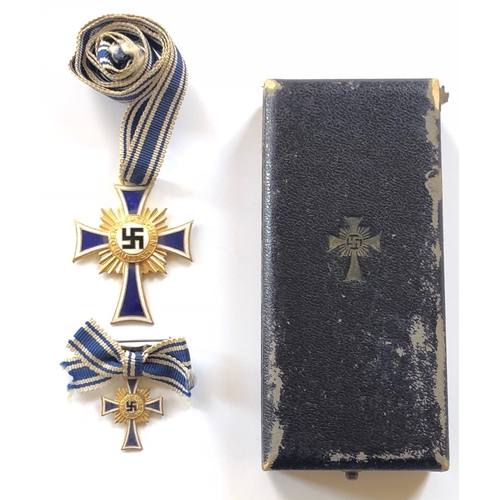 German Third Reich. 1st class Cross of Honour of the German Mother in case of issue with miniature.  A fine gilt example with blue and white enamelled arms and central black enamel swastika complete with long neck ribbon.  Reverse with facsimile Adolf Hitler signature. VGC.  Together in miniature on its tied ribbon. Housed in rather worn original Wilh. Deumer Kom.-Ges. Ludenshied fitted case of issue, the lid embossed with facsimile of the award.        Instituted by Adolf Hitler on 16th December 1938; 1st Class awarded for bearing 8 or more children for the Fatherland.