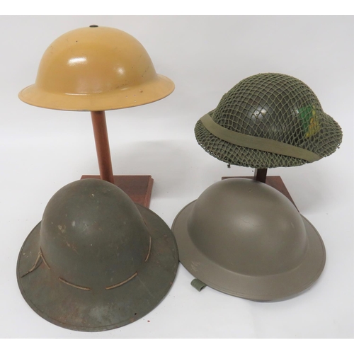 Four British Steel Helmets
consisting khaki yellow, repainted, MKII helmet.  Side brim drilled with 3 holes.  Black treated liner.  The frame dated 1939.  Early pattern, oval rubber crown pad ... Post war reissue helmet.  Black linen liner.  Cruciform crown pad ... Similar example with repainted badges.  Camo net.  Brown leather liner ... 1941 dated Zuckerman civilian high crown helmet.  Leather and webbing liner.  4 items.
