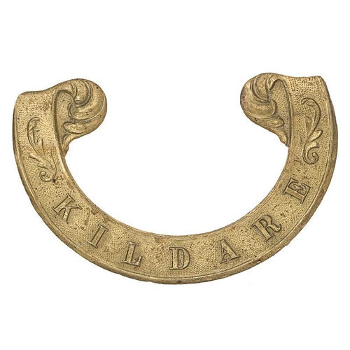 Irish Kildare Militia Victorian scroll pattern forage cap badge circa 1858-74.  Good scarce die-stamped brass universal cursive scroll with floreated finials bearing the raised legend KILDARE.  Opened pinched bent loop, the other lead soldered replacement absent. GC        Gordon Cummings Collection.