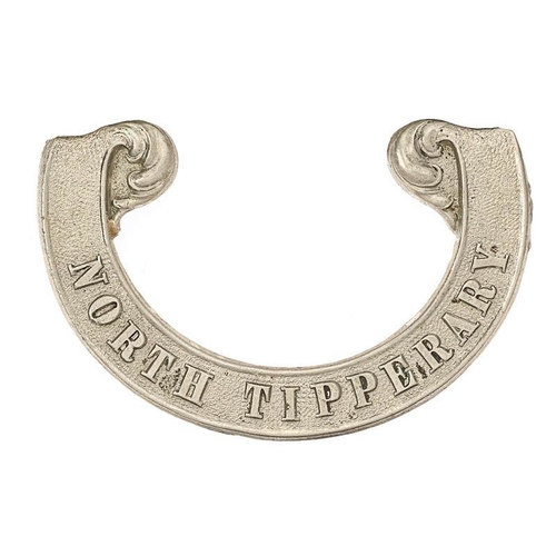 Irish North Tipperary Victorian scroll pattern forage cap badge circa 1858-74.  Good scarce die-stamped white metal universal cursive scroll with floreated finials bearing the raised legend NORTH TIPPERARY.  Opened pinched bent loop, the other lead soldered replacement absent. GC        Gordon Cummings Collection.