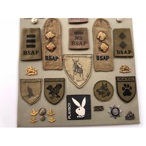 178 - British South African Police 44 items of insignia.  Board with good display of metal and cloth badge... 