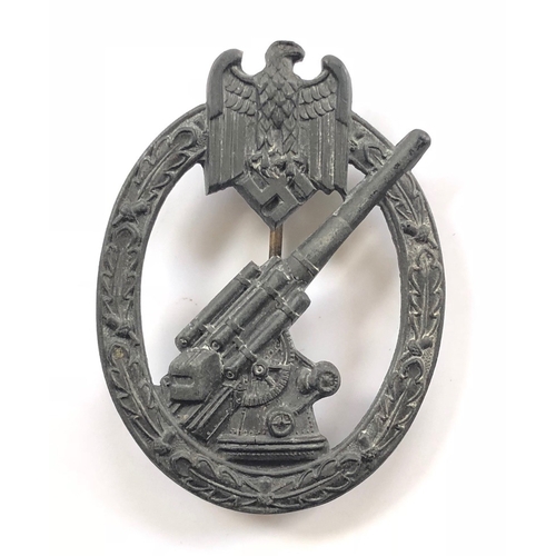 German Third Reich WW2 Army / Waffen-SS Flak breast badge. A good die-cast grey metal 88mm Ant-aircraft gun within oakleaf ornamented oval surmounted by eagle and swastika. Unusual brass hinged needle pin and securing hook. VGC Instituted 18th July 1941 and designed by Ernst Wilhelm Peekhaus.