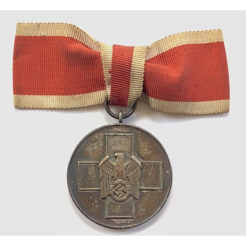 German Third Reich Social Welfare Medal.  A good silver plated example. The obverse with eagle and swastika superimposed on Geneva Cross; reverse with raised text Medaille für deutsche Volkspflege. Mounted as worn on ladies bow. Toned but generally VGC.        Previous German Red Cross awards superseded by the German Social Welfare Decoration 1st May 1939.
