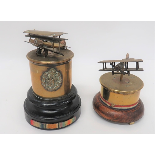 Two Trench Art Aircraft
consisting 13 pr. 1915 shortened case on wooden base.  The top with bullet bi-plane engraved "Souvenir Douai" ... Similar case on wooden base with mounted RFC badge.  The top bullet triplane loose.  2 items.