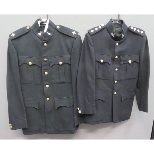 Two Post War Bedfordshire & Hertfordshire Patrol Uniforms
consisting black, single breasted, high collar tunic.  Pleated chest pockets with buttoned flaps.  Lower patch pockets with plain flaps.  Silvered collar badges.  Anodised Lt rank stars.  Brass regimental buttons . Internal tailors label named to Brett ... Matching overall trousers with red side lines ... Similar patrol tunic.  Silvered collar badges.  Anodised Captain rank stars and regimental buttons.  3 items.