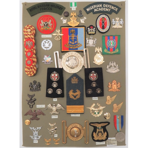 38 Items Of Insignia For Nigerian Forces
display board with good tabulated display of metal and cloth badges including white metal Nigerian Army Armoured Corps cap badge ... Anodised Air Force cap badge ... Anodised Nigeria Army Intelligence Corps buckle ... Bi-metal Nigerian Army Signals buckle ... Bullion embroidery Air Commodore shoulder strap.  38 items.  