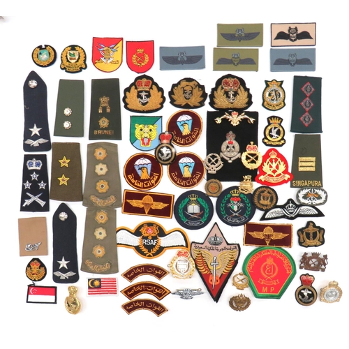 60 x Far East Badges
varied selection of loose badges including bullion embroidery Brunei Forces ... Anodised Malay cap badge ... Silvered Federation Of Malaya Police ... Various cloth badges ... Various rank shoulder straps.  60 items.
Bob Betts' collection. 