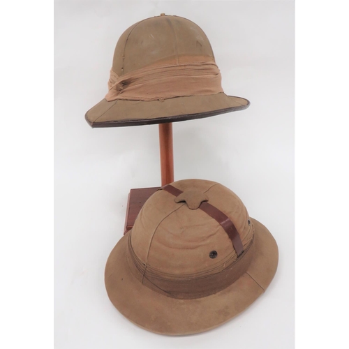 Two Various Pith Helmets
consisting an Indian made, military/civilian example.  Low, khaki crown with lower oval brim.  Leather strap across the crown.  Multi fold pagri band.  Leatherette sweatband.  Crown showing paper construction ... Military pattern helmet.  Khaki, six panel crown.  Pointed peak and rounded rear brim.  Linen pagri band.  Sweatband absent.  2 items.