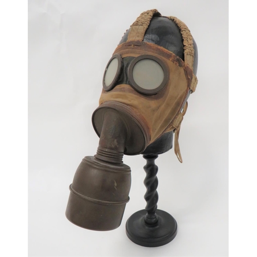 French WW2 TC38 Gas Respirator
tan, rubberised linen face mask with two circular eye lenses.  Green painted front mount with screw off filter.  Rear elasticated head mount straps.  Now mounted on a wooden stand.  