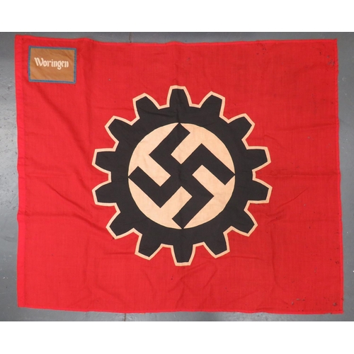 German Third Reich R.A.D. Woringen Standard
47 x 56 inch, red linen flag.  Central white and black, multi stitched, double sided cog wheel with stitched black swastika.  The top corner with blue edged brown felt and stitched "Woringen" to both sides of the standard.  Edge of flag with old pin holes.  Various stains and moth damage. 