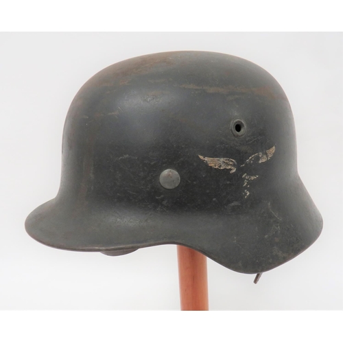 Third Reich German M1940 Luftwaffe Steel Helmet
dark grey/black steel shell with lower rolled edge brim.  The left side with Luftwaffe eagle 50% present.  Inner brim stamped "69" and "ET 64".  Alloy lining band with built in chinstrap loops.  Tan leather, eight tongue sweatband stamped "57".  Black leather chinstrap with alloy buckle.  Some service wear. 