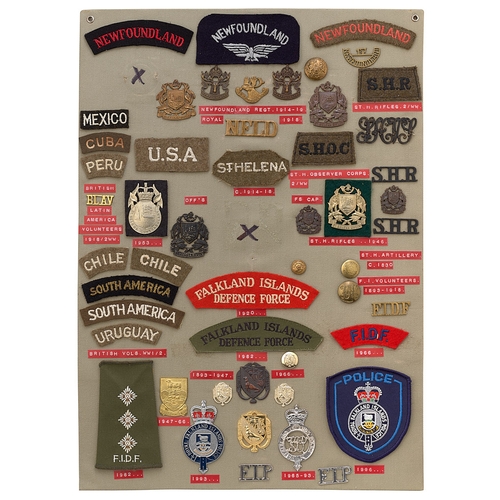 398 - 52 Newfoundland, St. Helena & Falklands badges etc.  Board with good display of metal and cloth badg... 